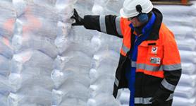 TOTAL Arbeiter vor gestapelten Plastikbeuteln
